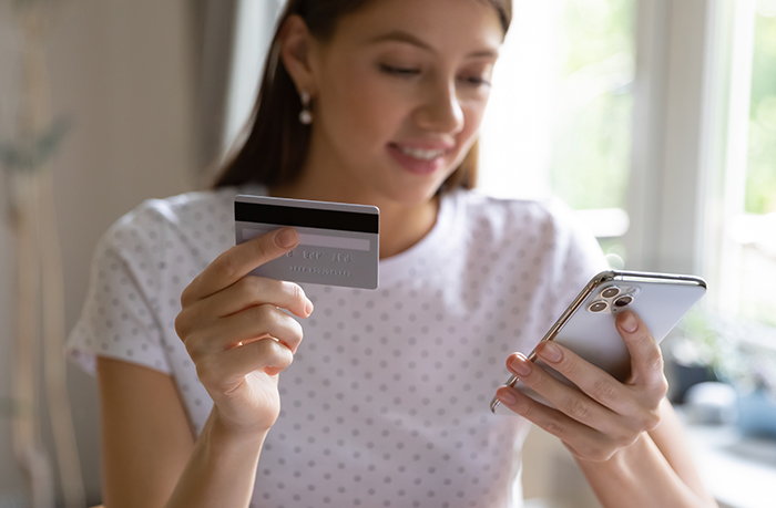 Tean gilr holding debit card and phone